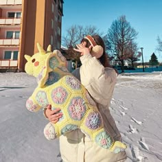 a woman holding a stuffed giraffe in the snow