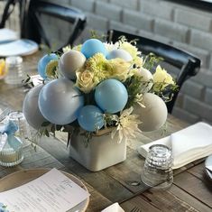 an arrangement of balloons and flowers in a vase on a dining room table set for two