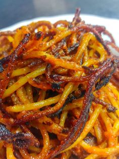 a white plate topped with cooked carrots on top of a wooden table next to a fork