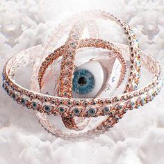 an eyeball is surrounded by many bracelets and rings on white furnishing