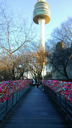 the walkway is lined with colorful flowers and trees in front of a tower that has a clock on it