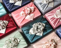 many different colored boxes with bows on top of each one, all wrapped in satin material