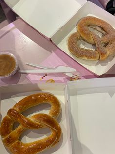 two large pretzels are sitting in boxes on a table next to some dipping sauce