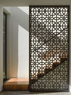 an intricate iron screen in the entry way to a house with stairs and windows on either side