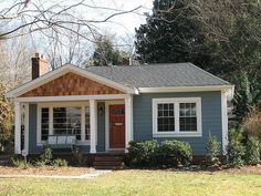 a small blue house with white trim and brown shutters on the front door is shown