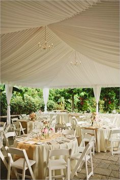 tables and chairs set up under a white tent