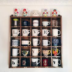 a wooden shelf filled with lots of different types of coffee mugs on top of each other