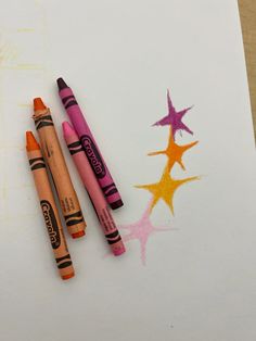 three crayons sitting on top of a piece of paper next to each other