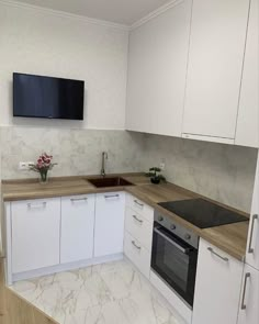 a kitchen with white cupboards and marble counter tops is shown in front of a flat screen tv mounted on the wall