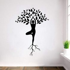 a woman is doing yoga in front of a tree with roots on the wall,