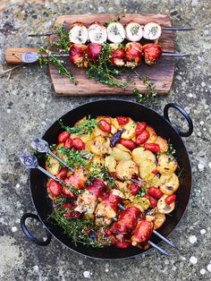 a pan filled with food sitting on top of a stone floor next to a cutting board