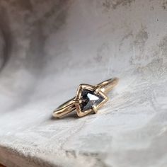 a gold ring with a black diamond in it sitting on a marble slabd surface