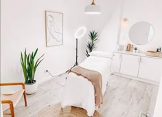 a bedroom with white walls and wood flooring is pictured in this image, there are two plants on the side of the bed