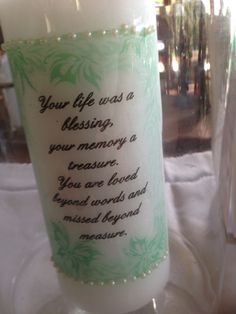 a candle with a message on it sitting next to a glass vase that says, your life was a blessing