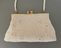 Elegant micro beaded vintage evening bag with a lovely raised floral pattern highlighted with pearlized tubular beads. It has a beautiful pearl closure & weight of a fine bag.  Collector worthy and heirloom quality bridal bag. READY TO SHIP DETAILS * Lined in champagne satin or silk with two side pockets , a lipstick pocket & "Ed.B Robinson" label * Measures 9" wide (at widest part)  and 6.5" in height with a 5 inch beaded handle MINT CONDITION See additional A Goddess Divine VINTAGE EVENING BAGS: http://www.etsy.com/shop/AGoddessDivine?section_id=13720333 View my complete collection including Bridal Sashes, Bridal Headpieces, Fascinators, Cuff Bracelets, Flower Girl Accessories and Vintage Evening Bags:   http://www.etsy.com/shop/AGoddessDivine A Goddess Divine creation designed for the G Vintage Veil, Bridal Clutch Purse, Flower Girl Accessories, Vintage Evening Bags, Bridal Purse, Bridal Bag, Beaded Evening Bags, Wedding Purse, Wedding Clutch