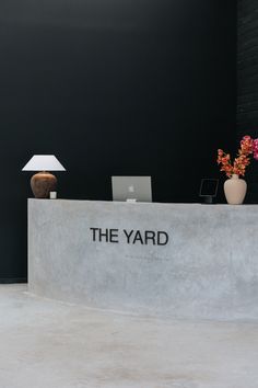 the yard sign is displayed in front of a desk with a lamp and vases on it