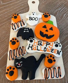 decorated halloween cookies with black cats, orange and white icing are on a platter