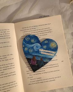 an open book with a heart shaped brooch sitting on top of it's pages