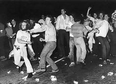 black and white photograph of people dancing in front of an audience at a party with confetti all over the floor