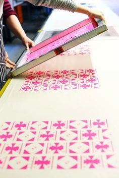 a person cutting out pink and white paper