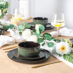 the table is set with black dishes and white flowers