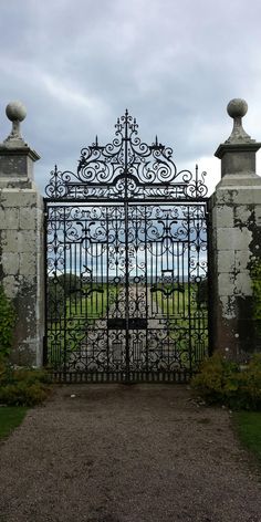 an iron gate in the middle of a grassy area