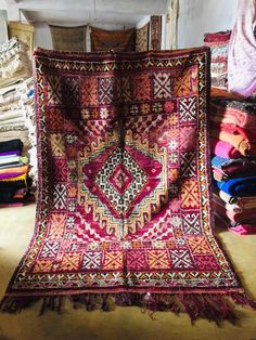 an old rug is laying on the floor in front of some other items and blankets