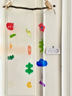 a bird is perched on a branch next to a colorful mobile hanging from a door