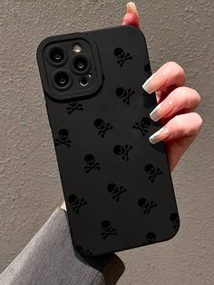 a woman's hand holding an iphone case with skull and crossbones on it