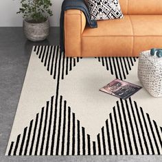 a living room with a brown couch and black and white rug