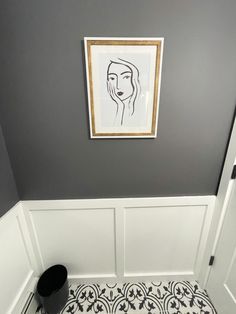 a black and white tiled floor in a bathroom with a framed portrait on the wall