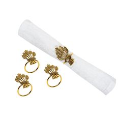 three gold rings and two napkin holders on top of a white napkin holder, with the napkin