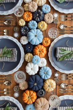 the table is set with pumpkins and silverware