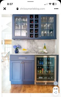 a kitchen with blue cabinets and wine bottles on the counter top in front of it