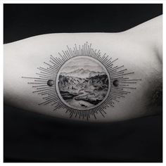 a man's arm with an image of mountains and sunbursts on it