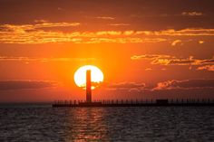 the sun is setting behind a lighthouse in the ocean