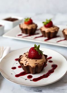 chocolate cupcakes with strawberries on top and sauce drizzled around them