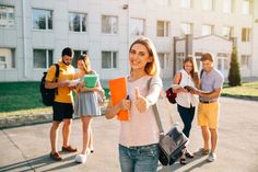 a group of young people standing in front of a building with backpacks and folders