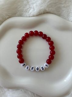 a red and white beaded bracelet with the word foss written on it in small letters