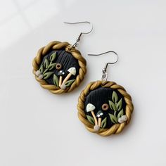 the earrings are made out of rope and decorated with black, white and green flowers