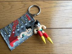 a keychain with two cartoon characters on it sitting on a wooden table next to a book