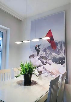 a dining room table and chairs with a painting on the wall behind it that has a red flag