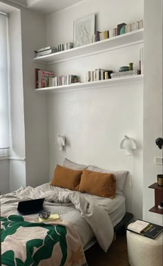 a bed sitting in a bedroom next to a window with lots of books on it