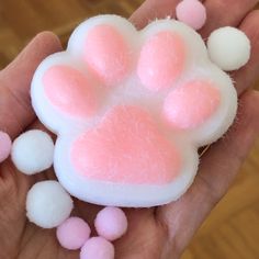 a hand holding a small pink and white dog paw toy with pom - poms