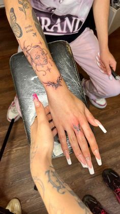 two people with tattoos on their arms and hands, one holding the other's hand