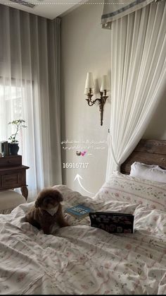 a teddy bear sitting on top of a bed next to a book in front of a window