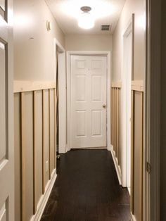 an empty hallway with wood floors and white doors