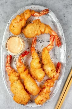 fried shrimp and dipping sauce on a plate with chopsticks