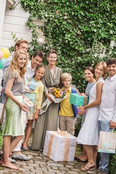 a group of people standing next to each other with gifts in front of some trees