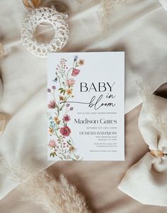 a baby is born card on top of a bed with white sheets and feathers around it